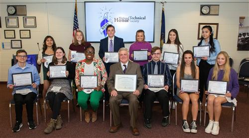 students pose for a photo seated with their induction certificates